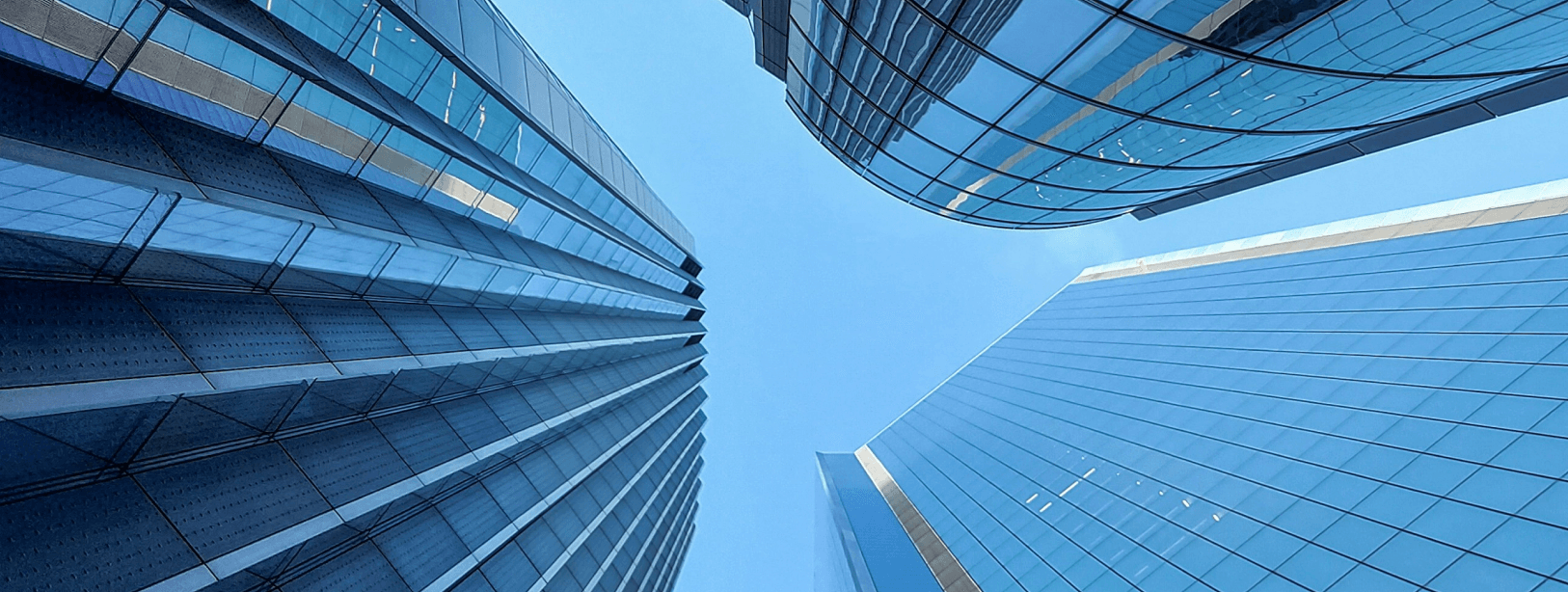 Upward view of modern glass skyscrapers with curved facades against a blue sky