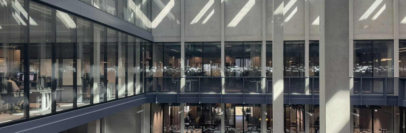 Modern office interior with dramatic diagonal lighting and glass-walled mezzanine showcasing contemporary architectural design