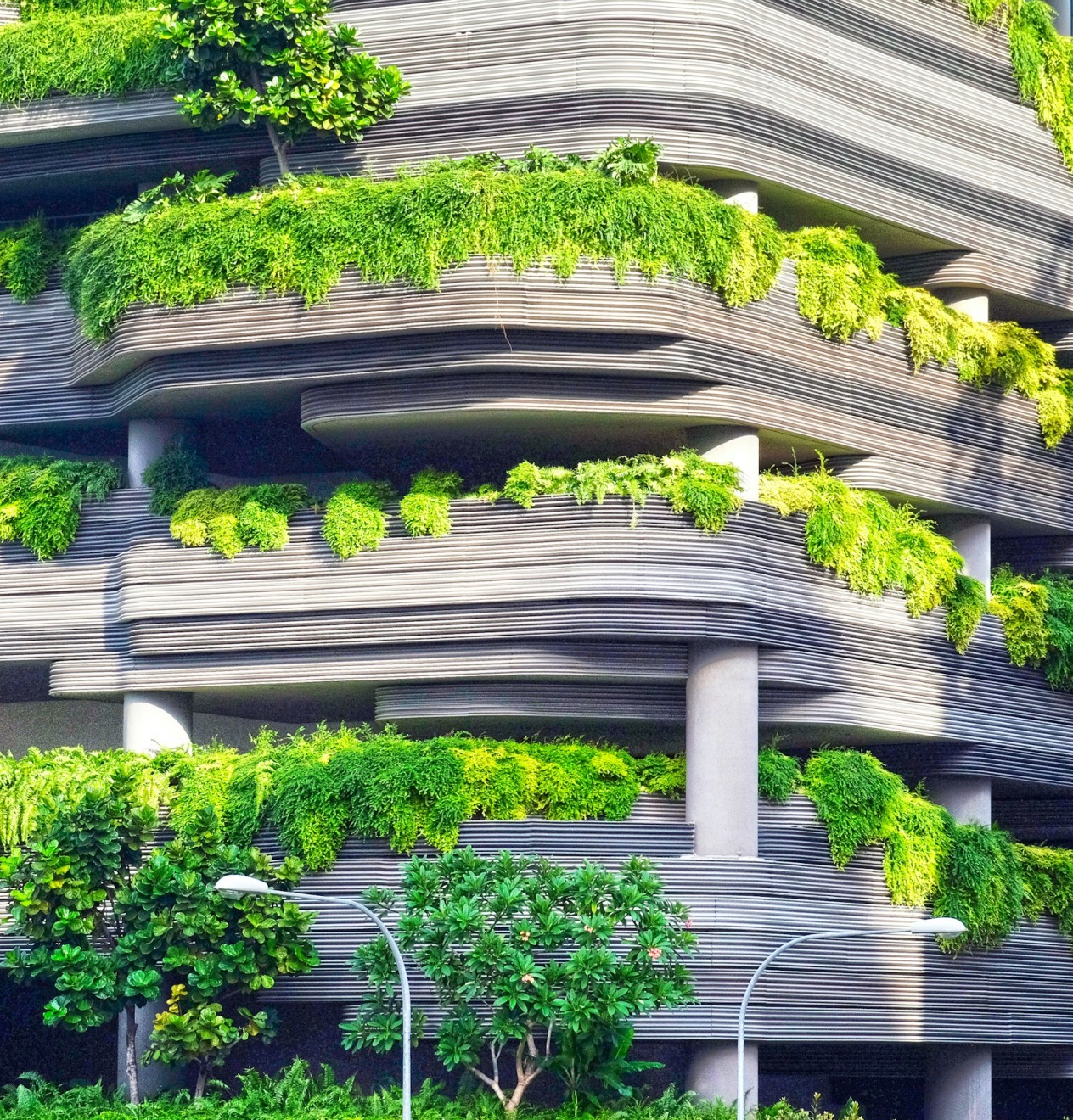 Modern architectural building with curved layers and cascading green plants